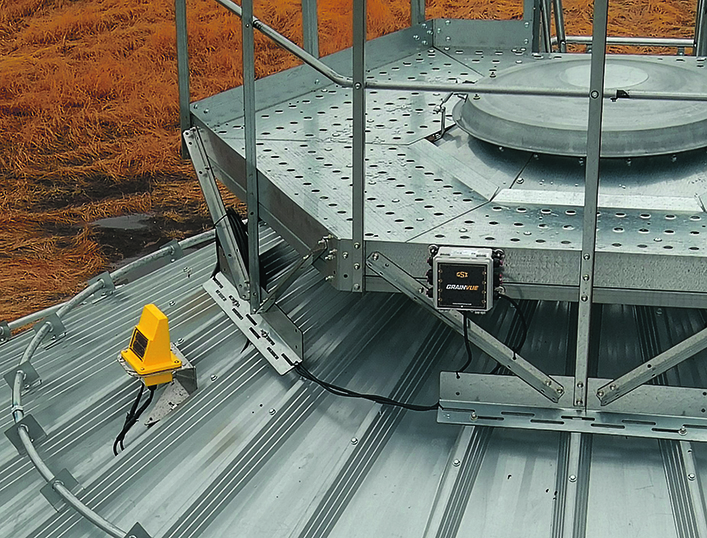 Safety railings and catwalks atop a large steel grain bin.