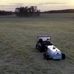 A side-by-side pulls a wheeled device the size of a small trailer over a field to measure carbon sequestration amounts.