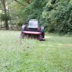 a zero-turn mower sits idle in the midst of mowing a lawn.