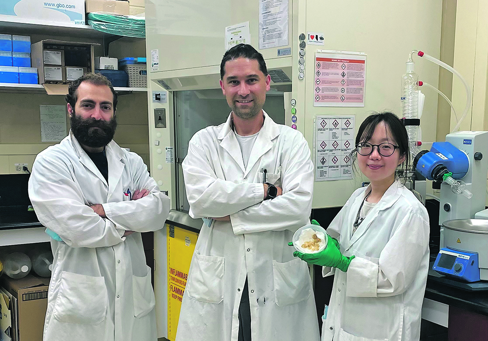 Three scientists in lab coats pose in alab.