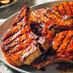 Pork chops hot off the BBQ sit in a plate ready to be served.