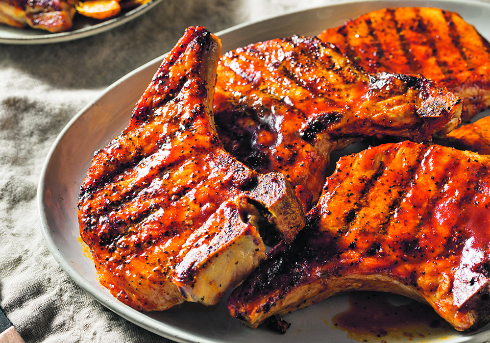 Pork chops hot off the BBQ sit in a plate ready to be served.