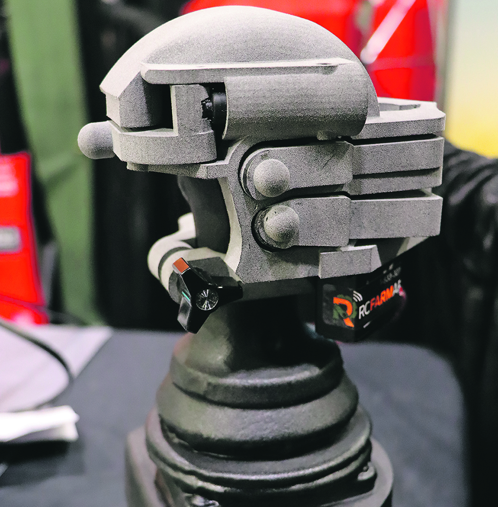 A remote-control device sits overtop of a tractor's armrest controls is displayed on a desktop.