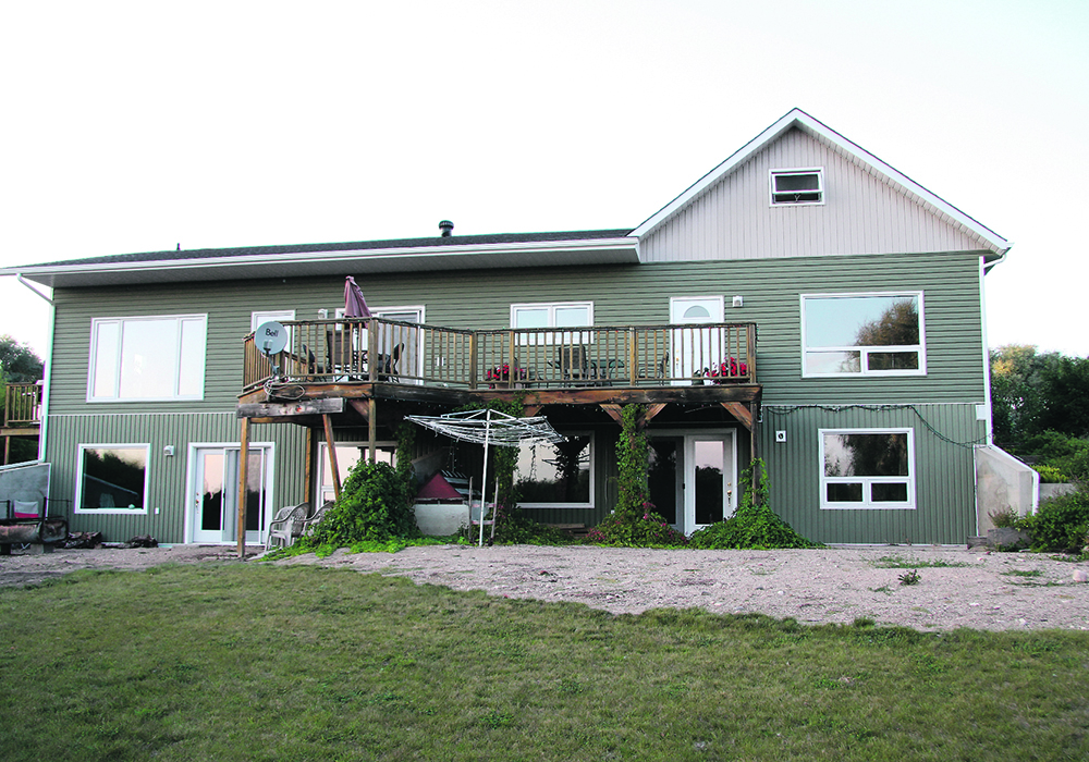 A two-level home with a deck on the second floor of the backside of the house.