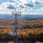 Aerial view of a rural cellular tower bristling with multiple antennae.
