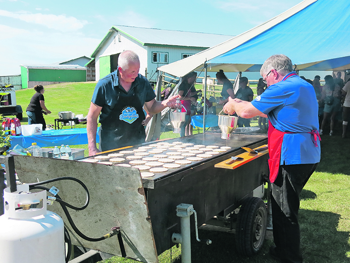 Volunteers flip pancakes on a large grill at a recent Alberta Milk-sponsored "Breakfast on the Dairy Farm" event.