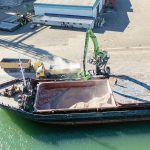 A drone's view of a ship having crop removed from its bulk hold while at dock.