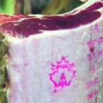 A "grade 'A'" meat inspection stamp is visible on a side of beef.
