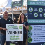 Trevor Scherrman and Megan Madden hold the sign displayed in front of their ScherGrain booth at Ag in Motion July 20. | Braedyn Wozniak photo