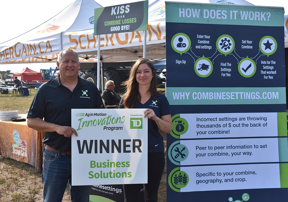 Trevor Scherrman and Megan Madden hold the sign displayed in front of their ScherGrain booth at Ag in Motion July 20. | Braedyn Wozniak photo