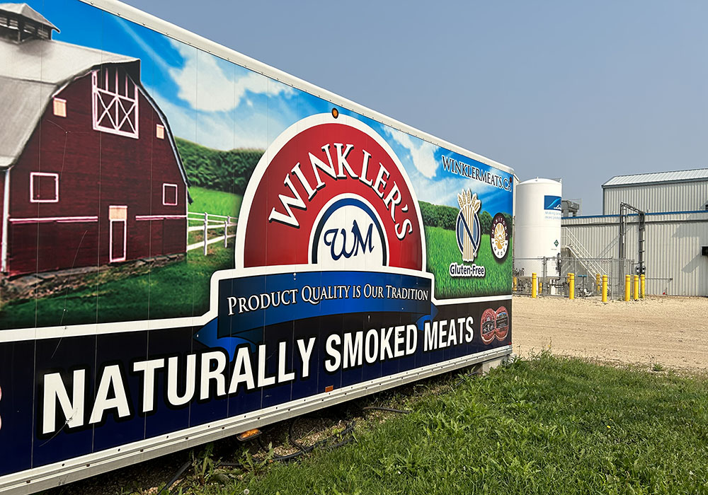 Large outdoor sign saying "Winkler's Naturally Smoked Meats."