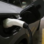 A charging handle protrudes from the side of a Volkswagen electric vehicle.
