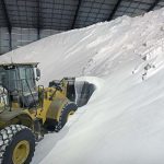 A payload scoops a bucket full of white fertilizer from a large pile.