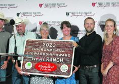 The Wray family holds up a carved wooden sign: "2023 Environmental Stewardship Award: Wray Ranch"