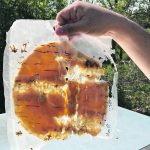 a backlit plastic back of an amber coloured substance being held up by a hand