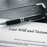 A black and silver pen on top of a paper that says "last will and testament"