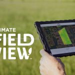 Promotional image of a farmer holding a tablet with the "FieldView" word logo to the left of it.