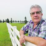 Reg Shandro leans on a fence.