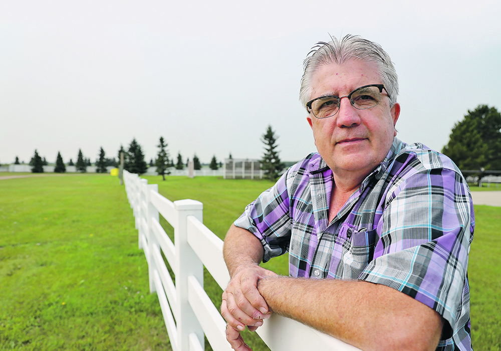 Reg Shandro leans on a fence.