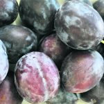 A close-up photo of some ripe plums on a counter.