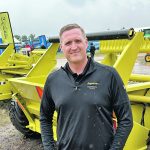 Derek Molnar of Degelman stands in front of one of the company's rock pickers at the Ag in Motion farm show in July of 2023.