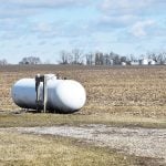 A large propane tank sits on the edge of a field.