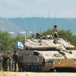 Israeli soldiers stand beside a tank near their country’s border with Lebanon Oct. 16. Israel’s war with the Gaza Strip has also increased tensions on the Israeli-Lebanese border. | Reuters/Lisi Niesner photo