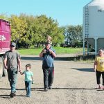 Geoff Hoyme and his son, Garrett, walk across their farmyard with Barb and Harry DeWindt while Otto sits up high. | Mary MacArthur photo