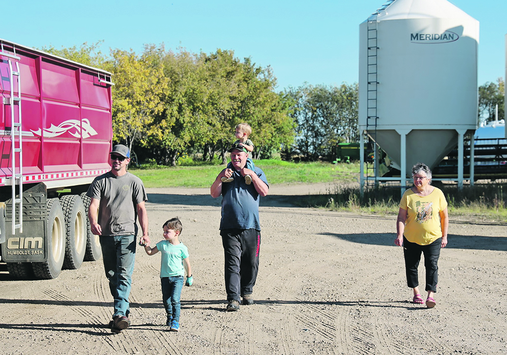 Geoff Hoyme and his son, Garrett, walk across their farmyard with Barb and Harry DeWindt while Otto sits up high.  |  Mary MacArthur photo