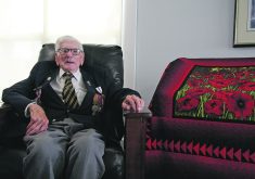 Second World War veteran Tracy Cross, wearing his service medals, sits beside the poppy quilt made for him by Linda Hanline, who works at Cypress Lodge in Maple Creek, Sask., where he now lives.  |  Karen Briere photo