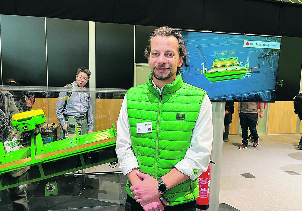 John Deere’s Jonathan Edwards stands in front of the company’s new Active Slope Adjustment for combine cleaning shoes at Agritechnica. | John Greig photo