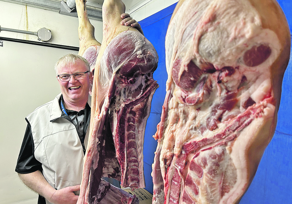 Chair Andy Cardy stands with the winning pork carcass sides at a competition held during the recent Brandon Hog and Livestock Show.  |  Ed White photo