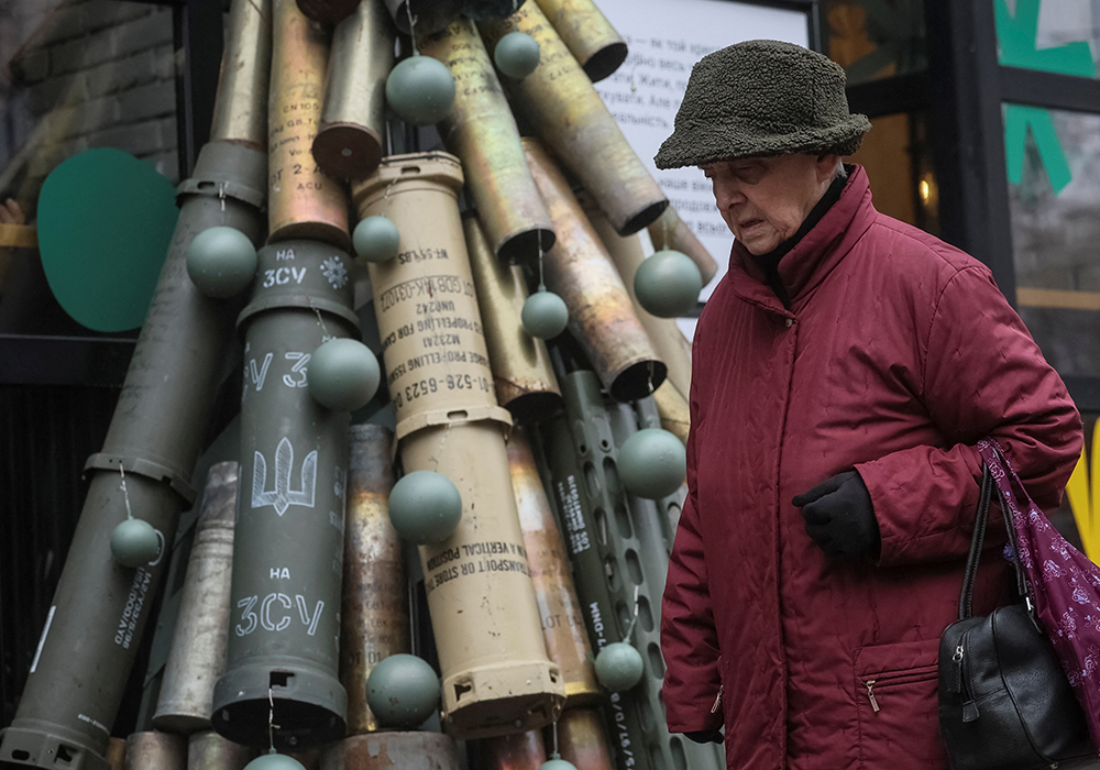 A woman passes by a symbolic Christmas tree made from used artillery shells and parts of rockets that have been brought to the Ukrainian capital from the front line. | Reuters/ Gleb Garanich photo