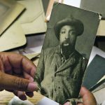 Cheryl Foggo examines a photograph of John Ware in a scene from her National Film Board documentary, John Ware Reclaimed. | NFB photo