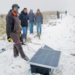 Tour attendees check out Brett McRae’s solar fencing system during a field tour last month. | Alexis Stockford photo