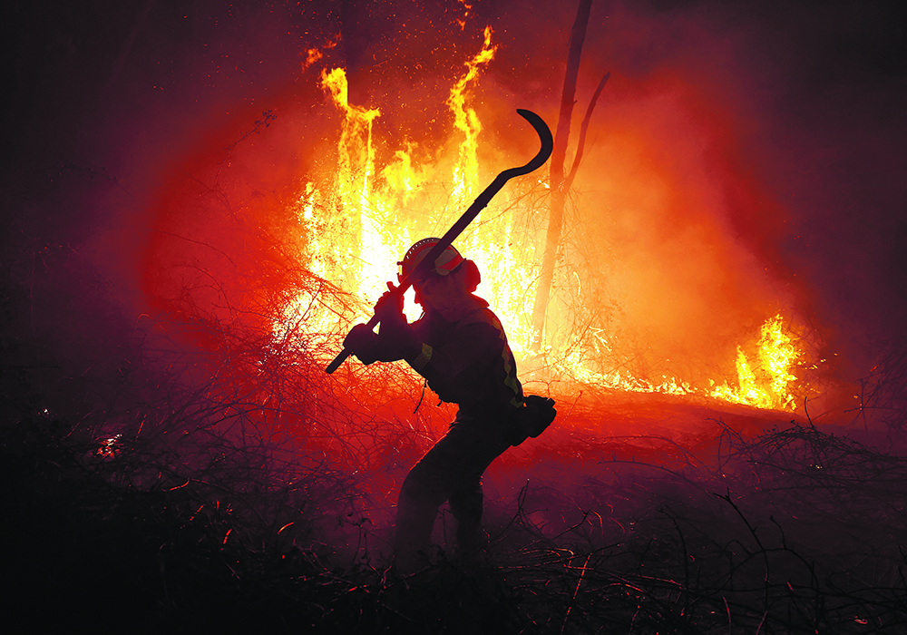 A firefighter tackles a forest blaze during an outbreak of wildfires following a prolonged dry spell and unseasonably high temperatures in Asturias, Spain, last March.  |  Reuters/Vincent West photo