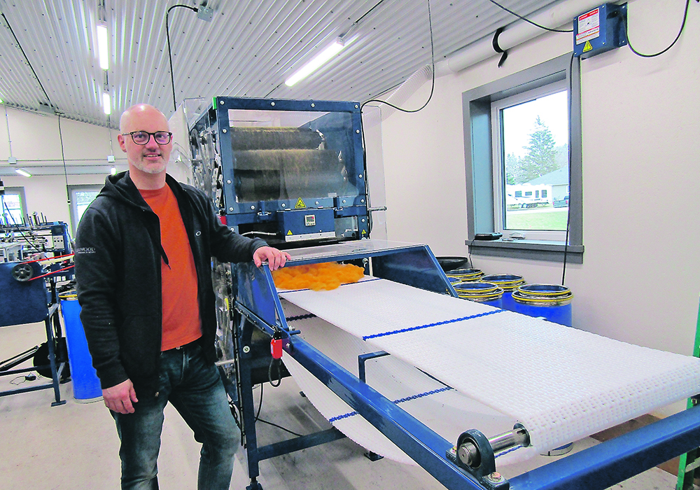 Bryan Driedger stands next to the Austin Woollen Mill’s wool carding machine.  |  Donna Gamache photo
