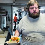 Brady Peterson, owner and chef of Pete’s, a barbecue restaurant, prepares a sandwich in Smith Center, Kansas. His business is one of many feeling the pinch as American farmers face falling incomes. | Reuters/Heather Schlitz photo