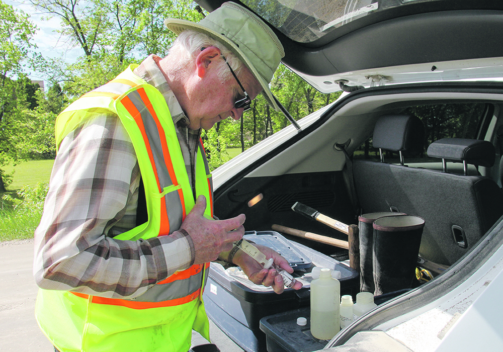 Ken Boese strains a water sample into a bottle to be tested for phosphorus content.  | Geralyn Wichers photo