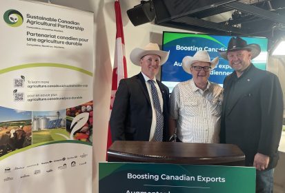 Nathan Phinney, Lawrence MacAulay and Eric Bienvenue wearing cowboy hats in front of a Sustainable Ag Partnership banner