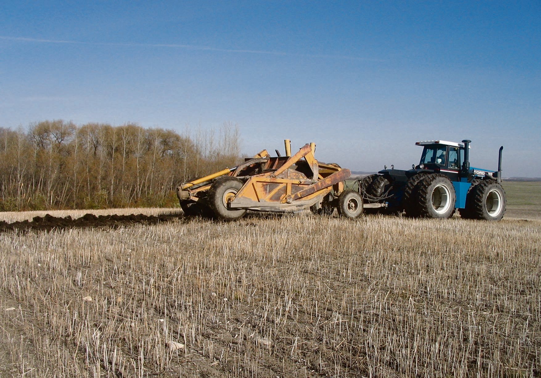 Danny Hacault drops 10 cm of topsoil back on the top of a knoll at his farm near Swan Lake, Man.  Hacault participated in a University of Manitoba field experiment, which determined that moving soil from the lower slopes can drastically improve yield on the top of the knoll, by as much as 133 percent.