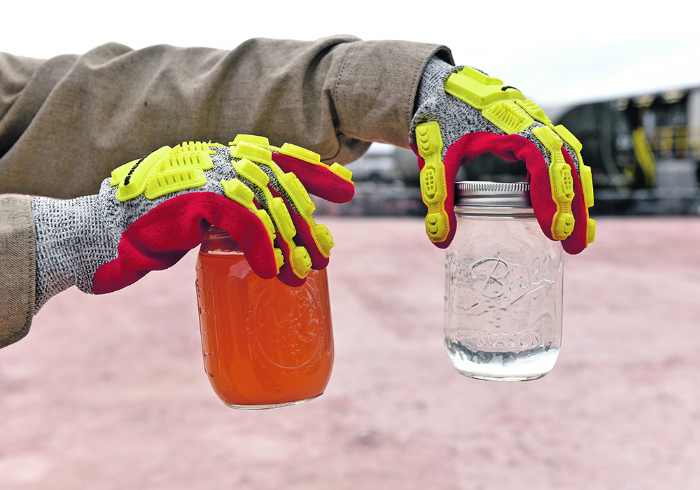 A worker holds up a jar of produced water, left, and recycled water at a water recycling facility owned by Exxon near Carlsbad, New Mexico.  |  Reuters/Nick Oxford photo