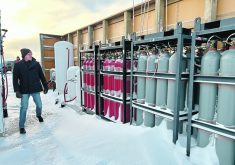 A visitor to Curtis Hiebert’s farm near Sperling, Man., glances at tanks that are part of the operation’s ammonia production plant. He is the first producer in Canada to have such a system, which allows a farmer to make their own anhydrous ammonia fertilizer using electricity and water. | Robert Arnason photo