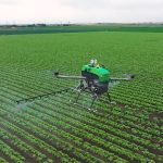 An agricultural sprayer drone flies over a field.