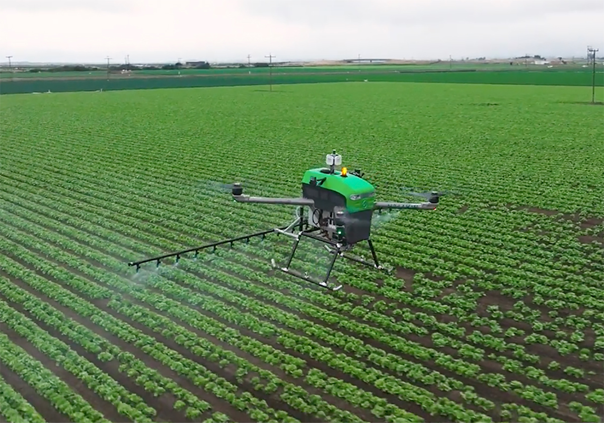 An agricultural sprayer drone flies over a field.