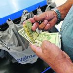 A customer counts his cash at the checkout lane of a Walmart store in the Porter Ranch section of Los Angeles