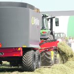 A feed mixer is towed behind a tractor on a cattle ranch.