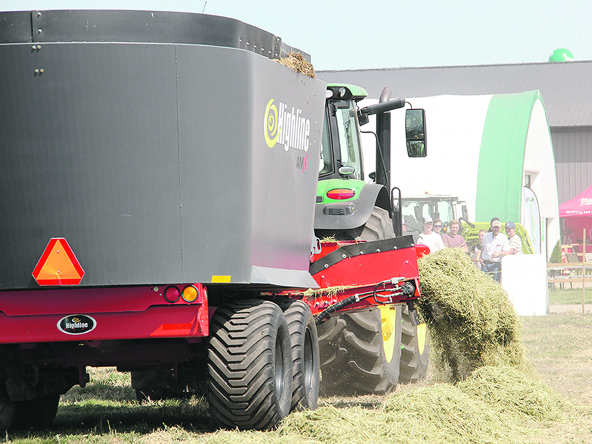 A feed mixer is towed behind a tractor on a cattle ranch.