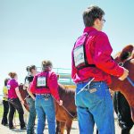 A line of 4-H beef competitors stand at the head of their animals.