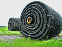 Two large rolls of tile drainage tubing sit in a field ready to be installed.